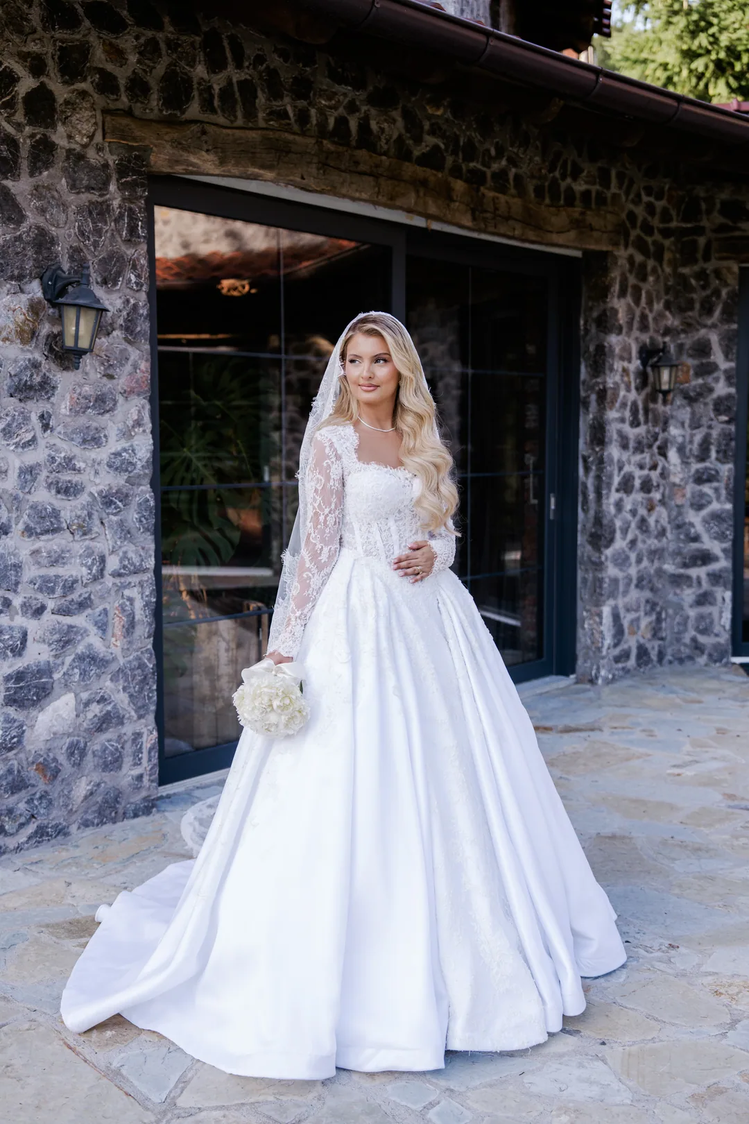 Bride with her bouquet in front of a stone house