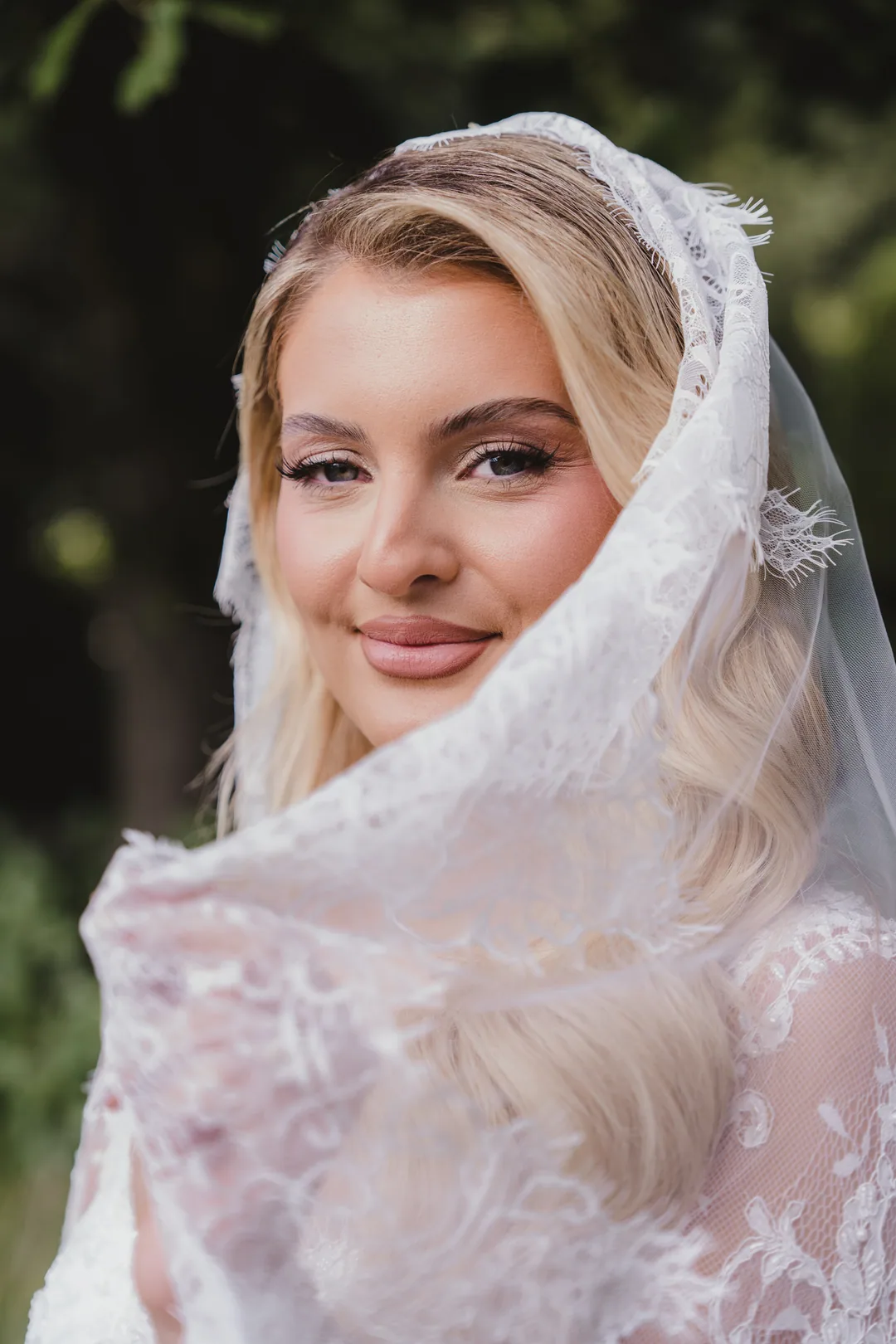 Bride in a lace veil looking straight into the camera