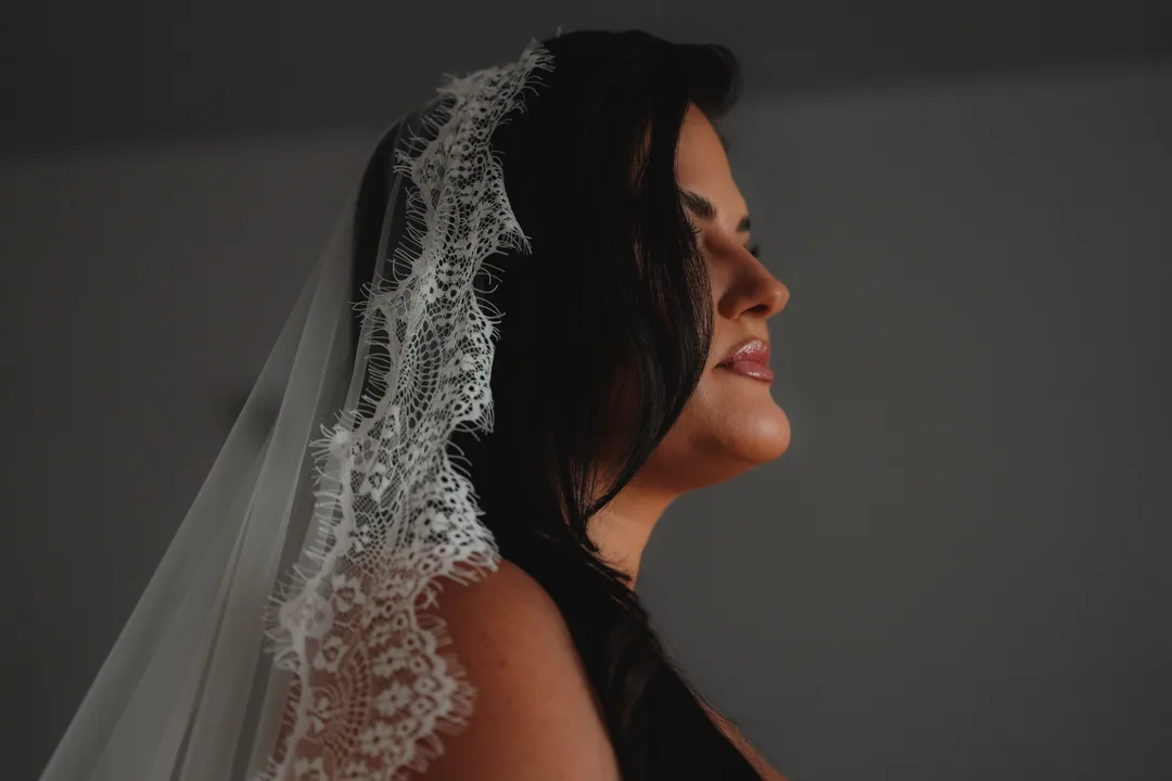 Bride in profile under a lace-edged mantilla, eyes closed, smiling