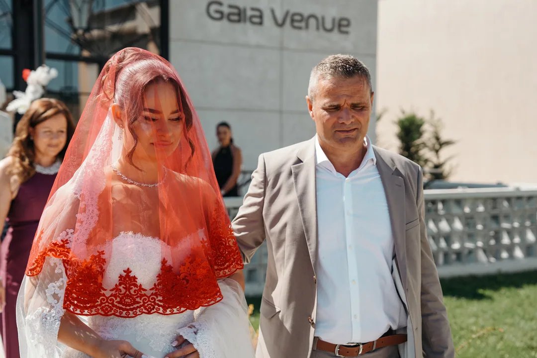 Bride in a red lace veil walking out with her family around her