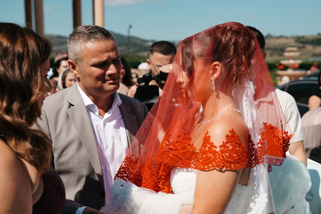 Bride in her red veil face to face with her father as she leaves