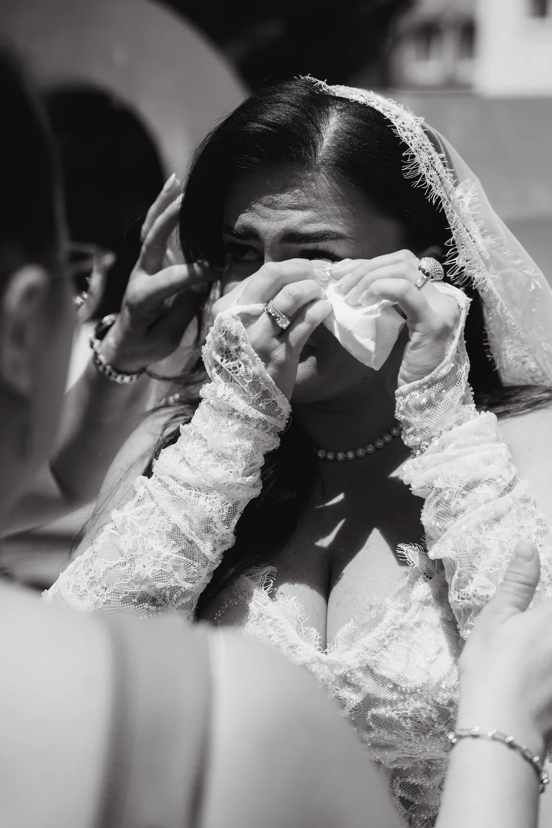 Bride wiping away tears with a handkerchief, in black and white