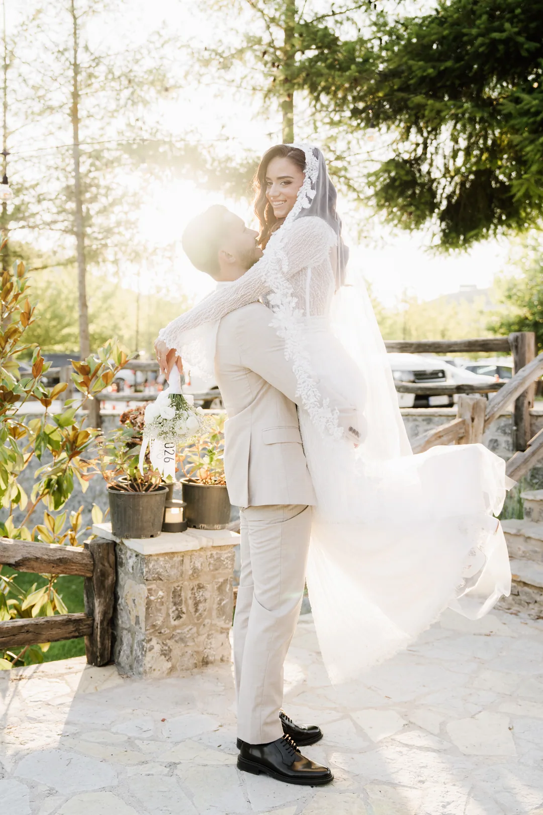 Bride laughing as the groom lifts her off the ground