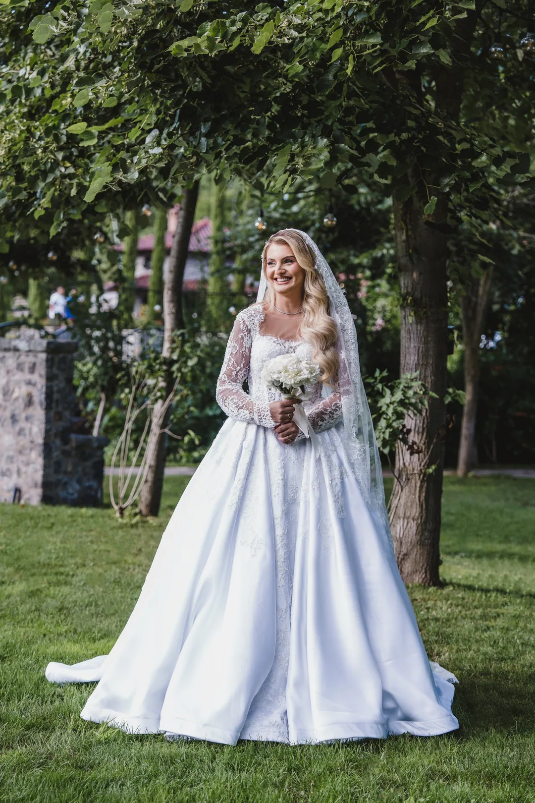 Bride smiling in a garden, a small bouquet in her hands