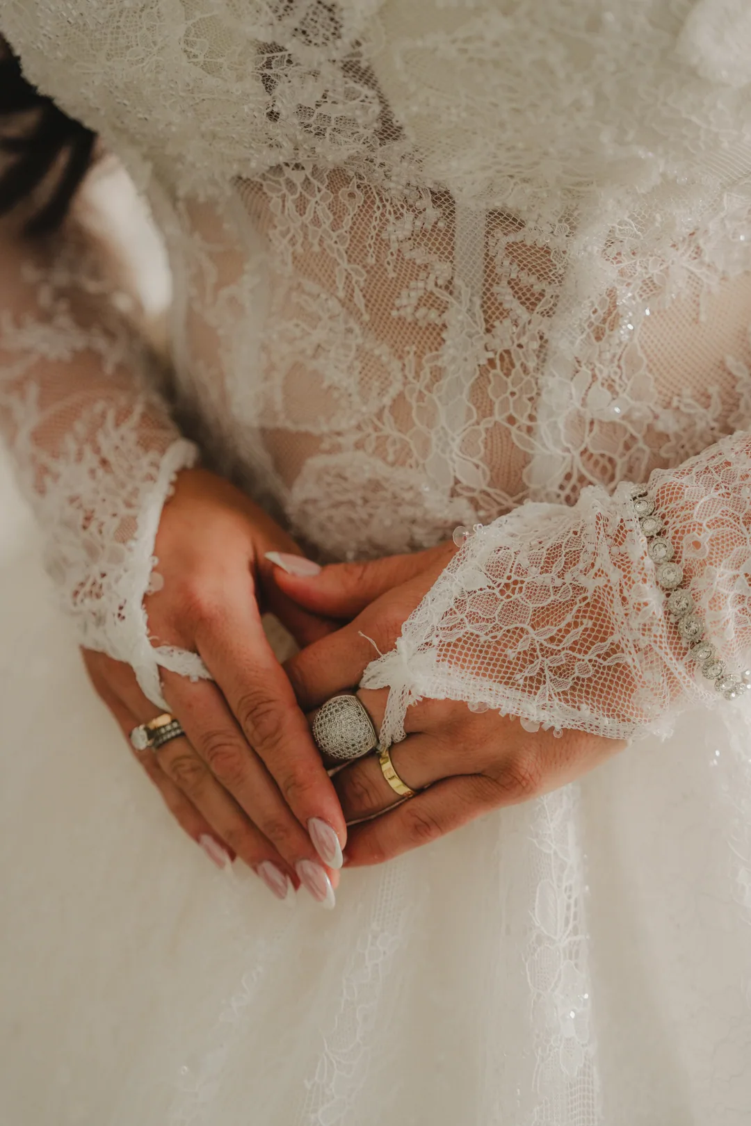 Bride's hands and rings resting on her lace bodice