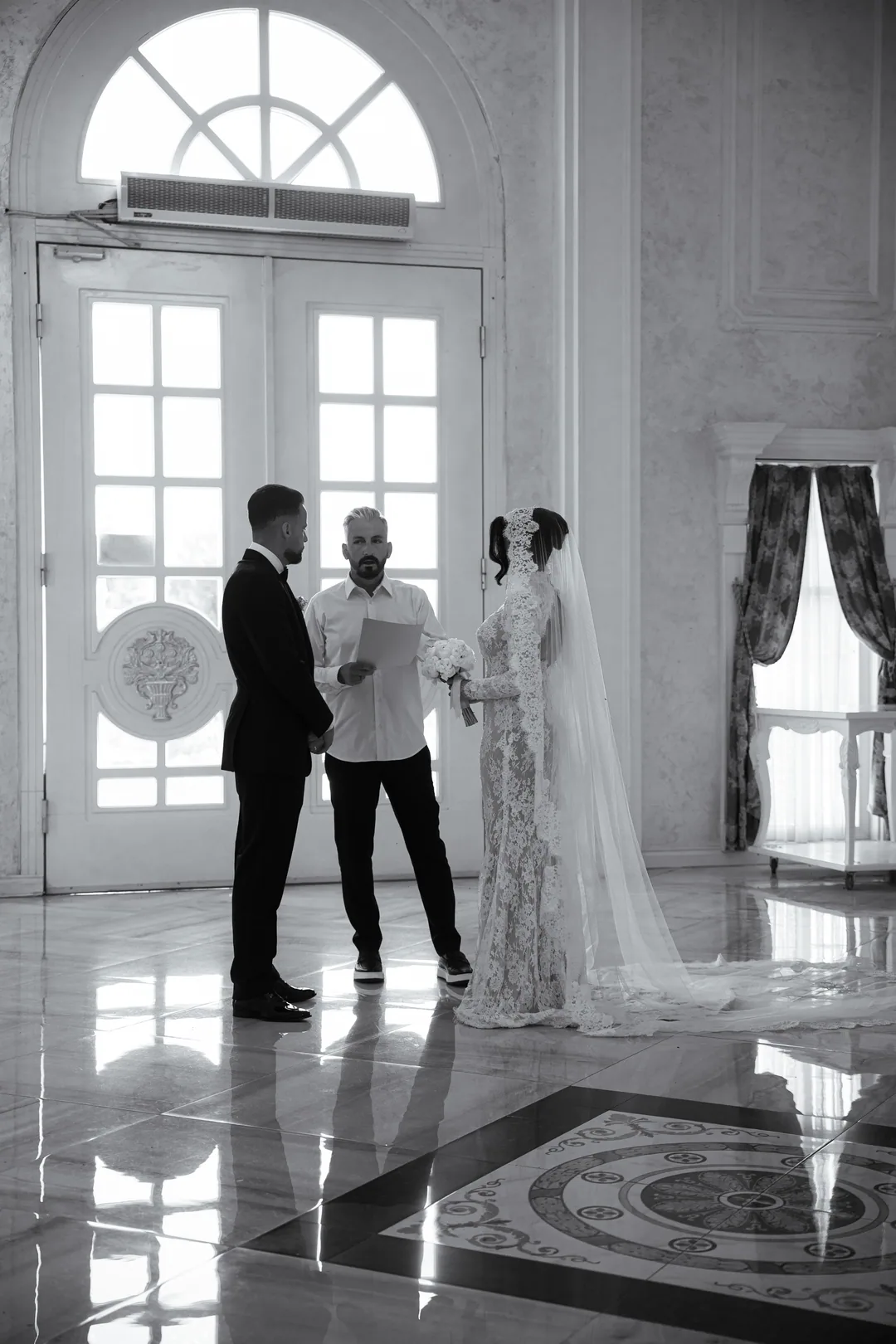 Civil ceremony in a white hall, the registrar reading to the couple, in black and white