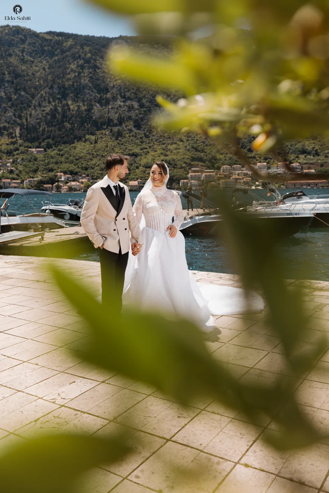 The couple by the water, seen through leaves in the foreground