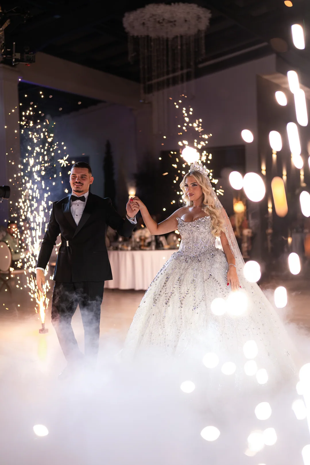 Bride and groom dancing between sparkler fountains in the fog