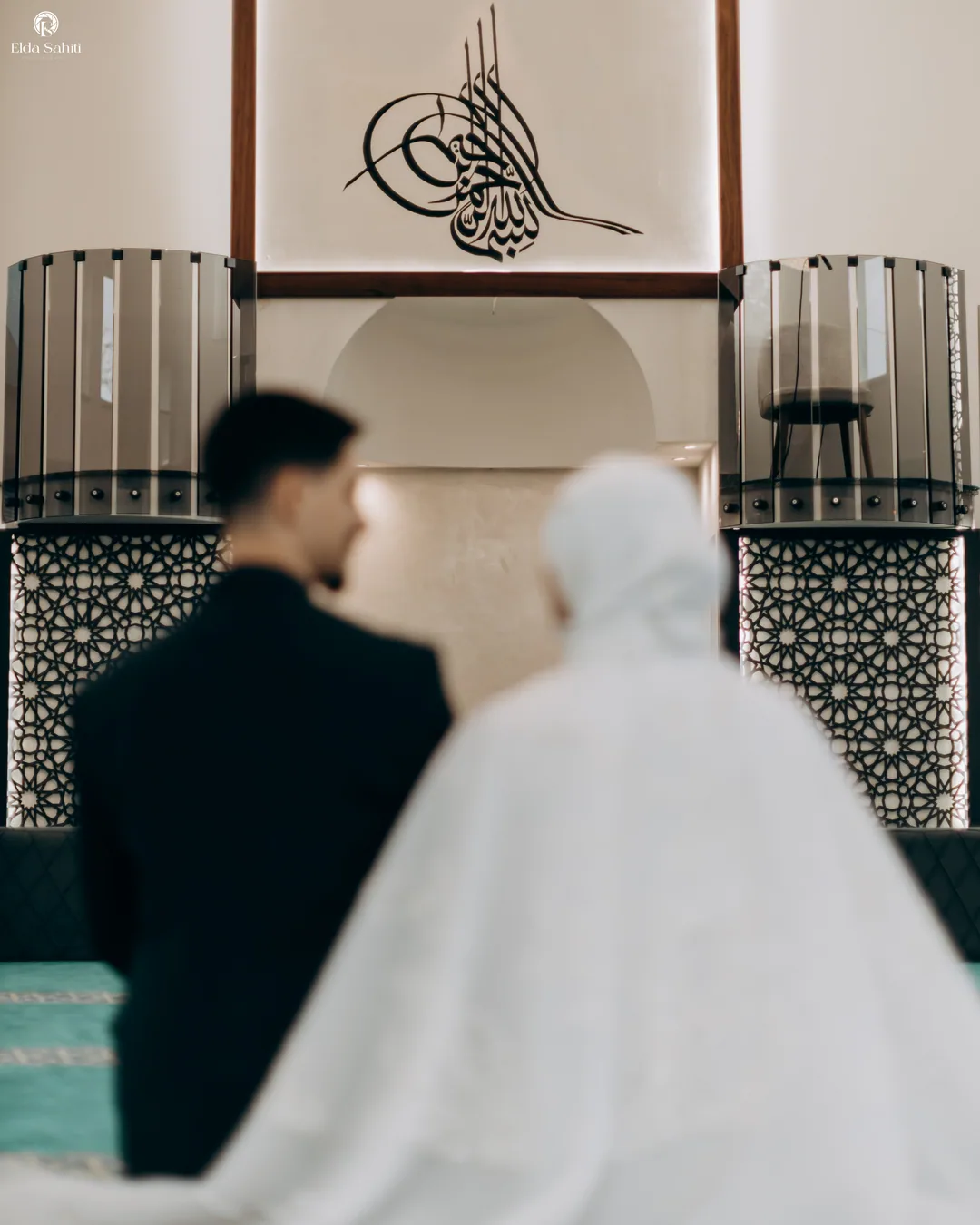 Bride and groom kneeling before the mihrab, calligraphy above them