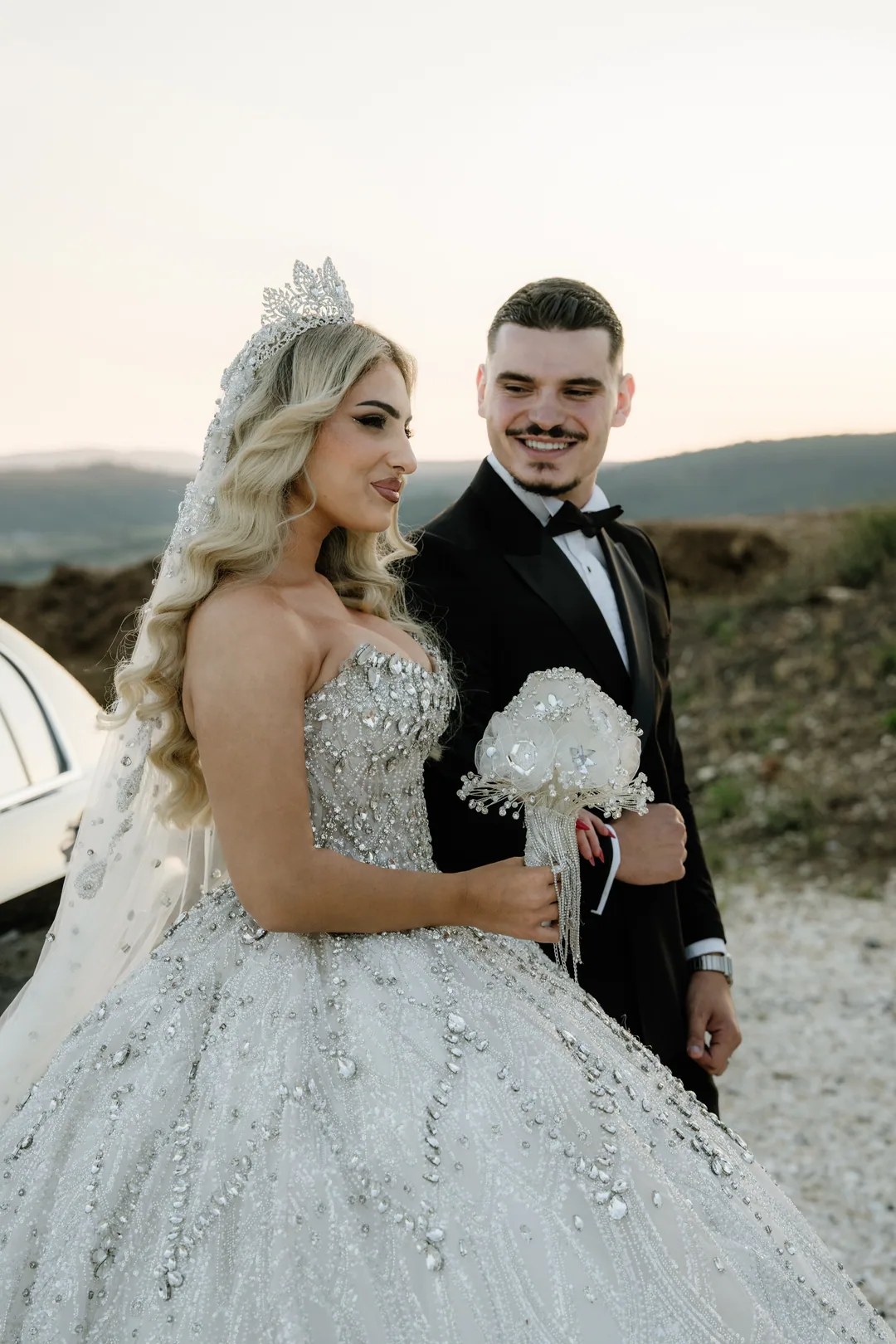 Bride and groom laughing together, the hills behind them in evening light