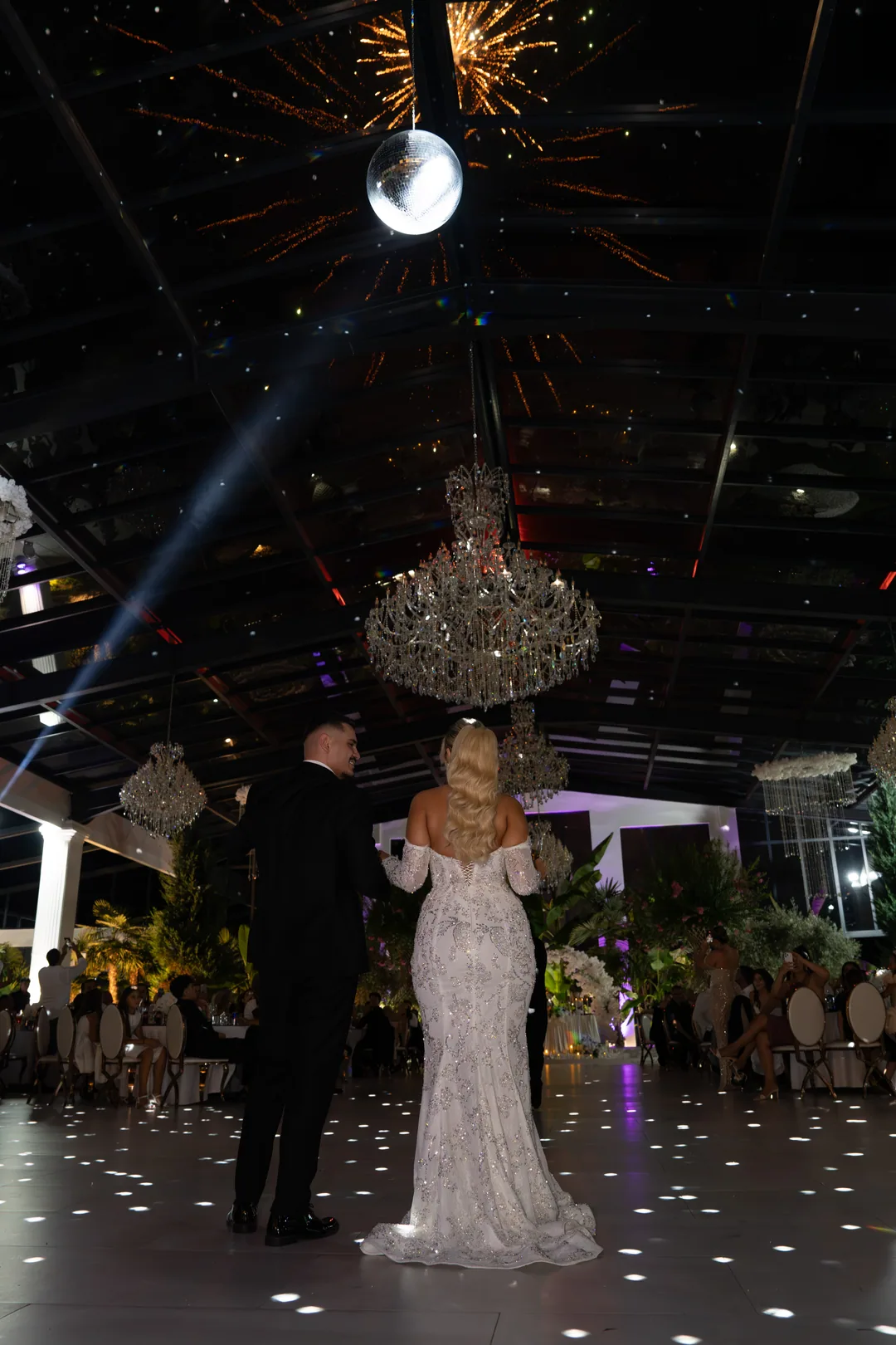 Couple seen from behind on the dance floor as fireworks burst under the roof