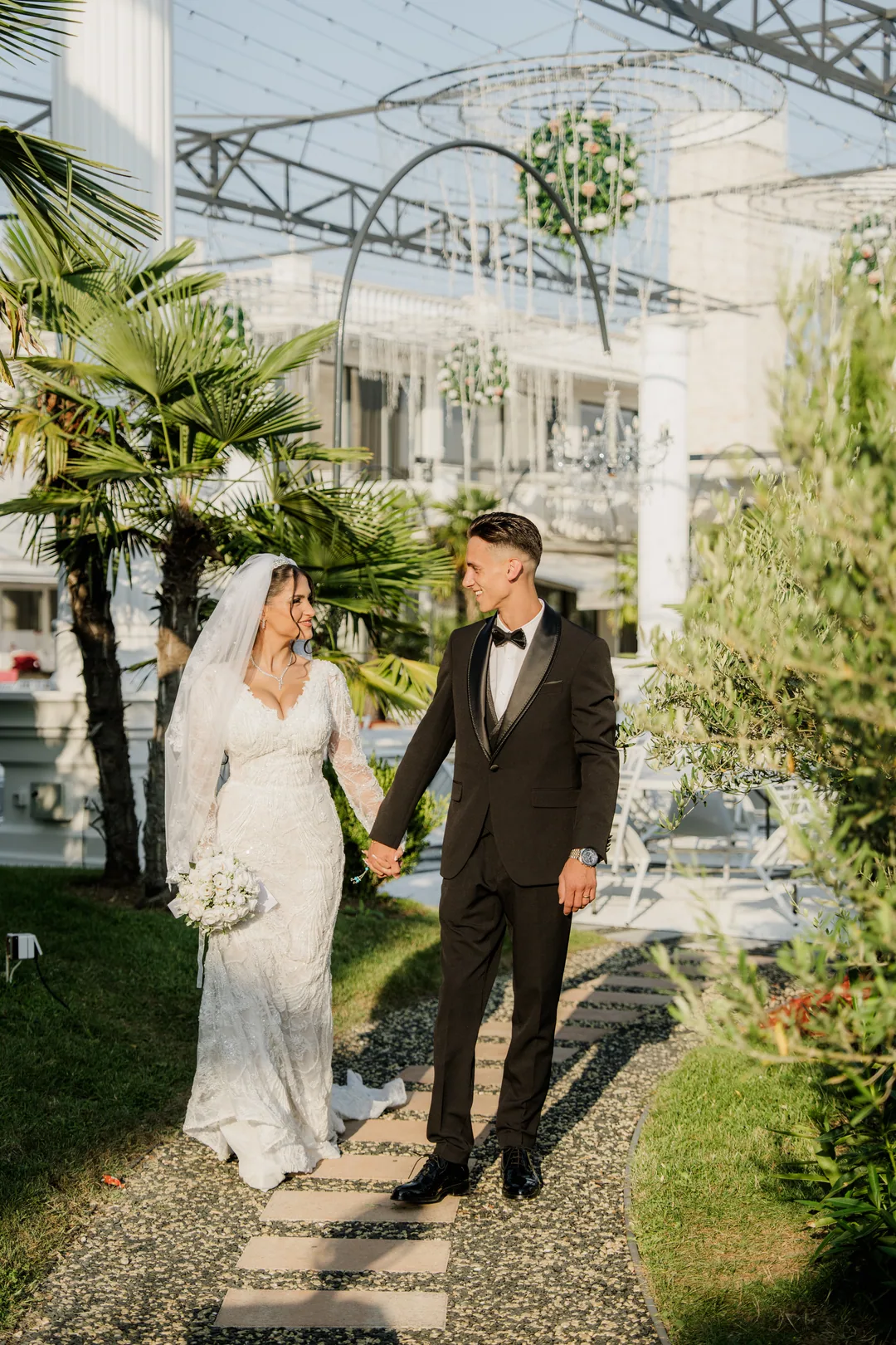 Couple walking hand in hand along a stepping-stone path among palms