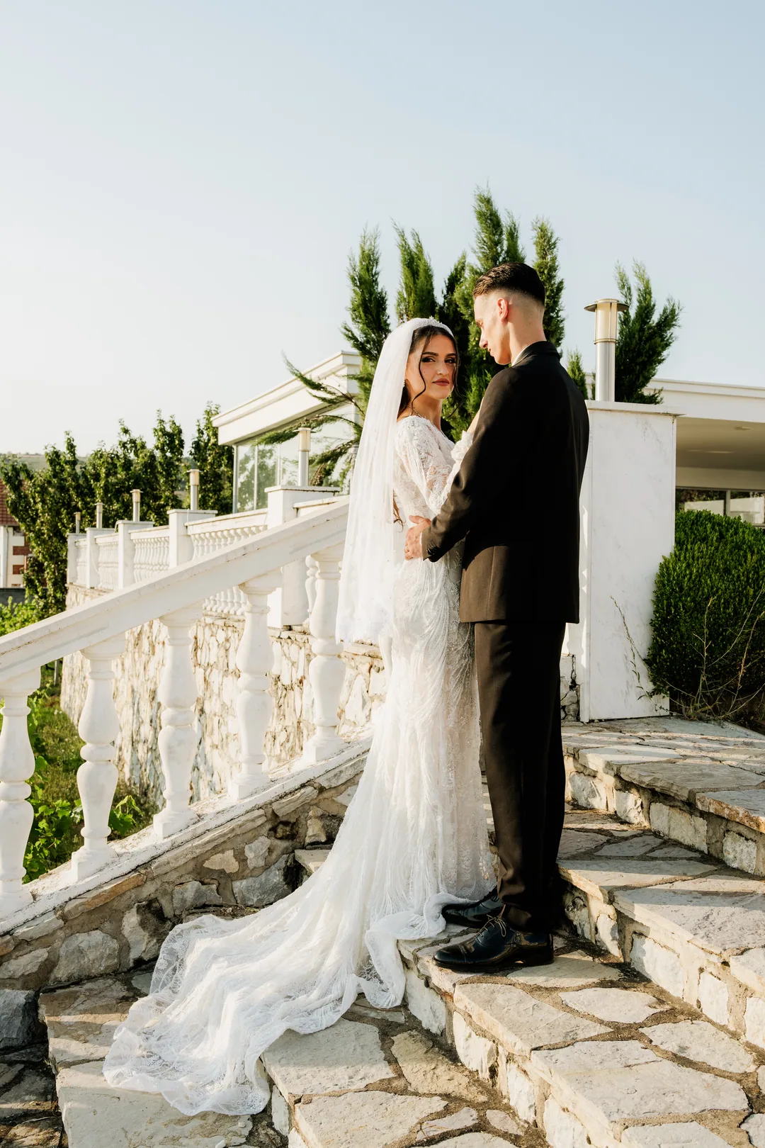 Couple on the white stone steps, her train cascading down behind them
