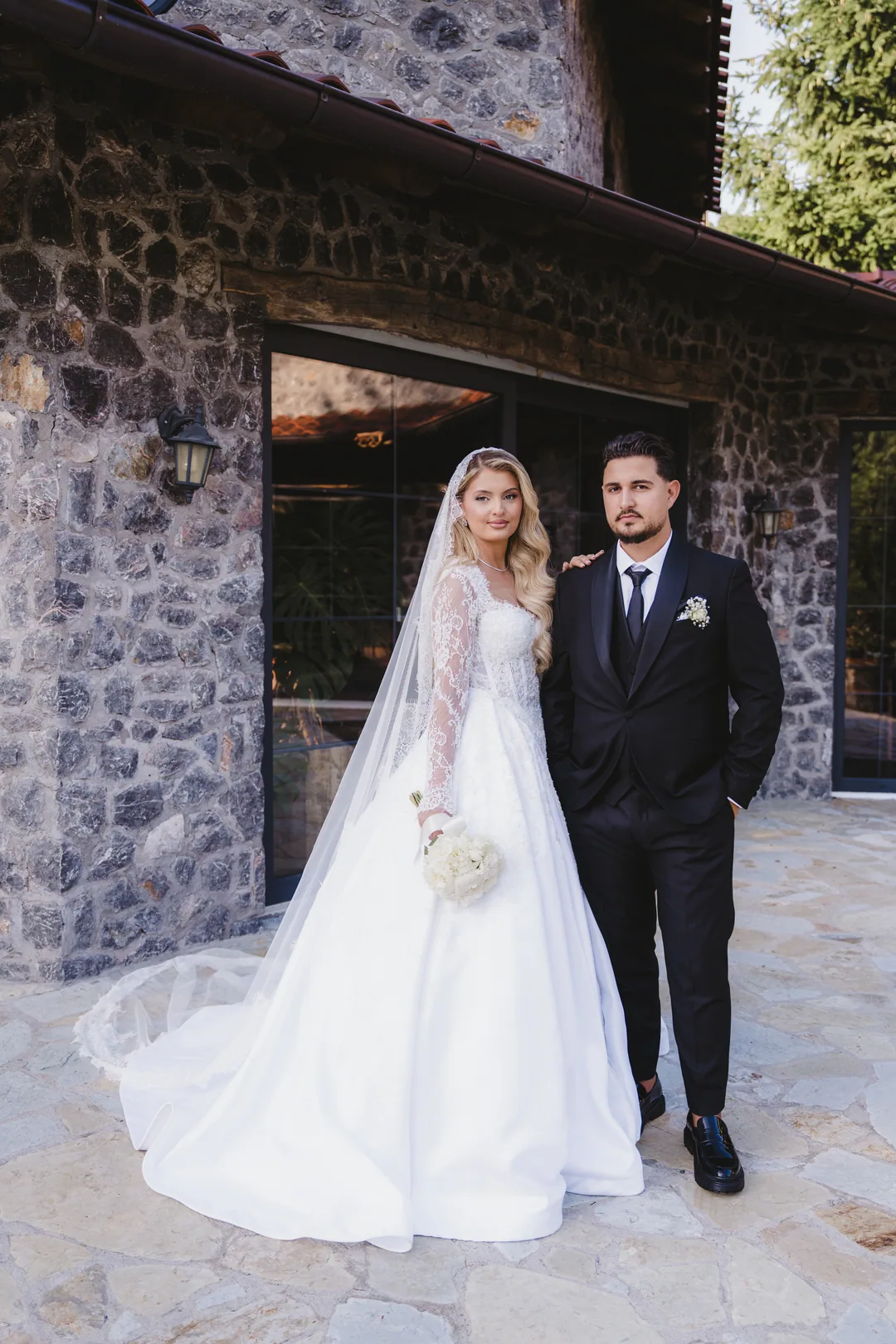 Bride and groom side by side in front of the stone house