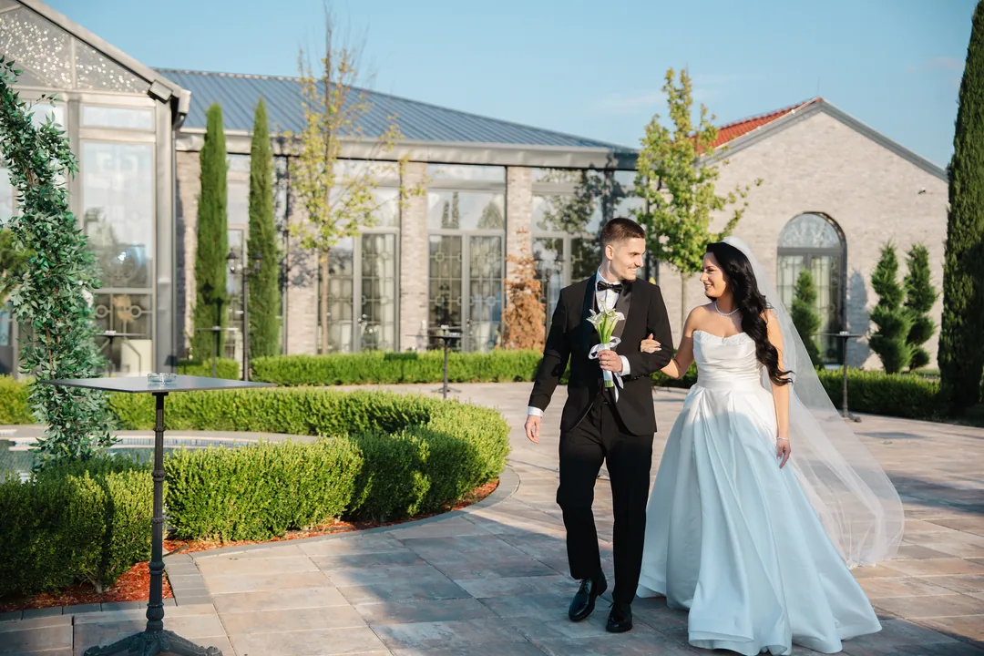 Couple strolling arm in arm through the garden of a glass pavilion