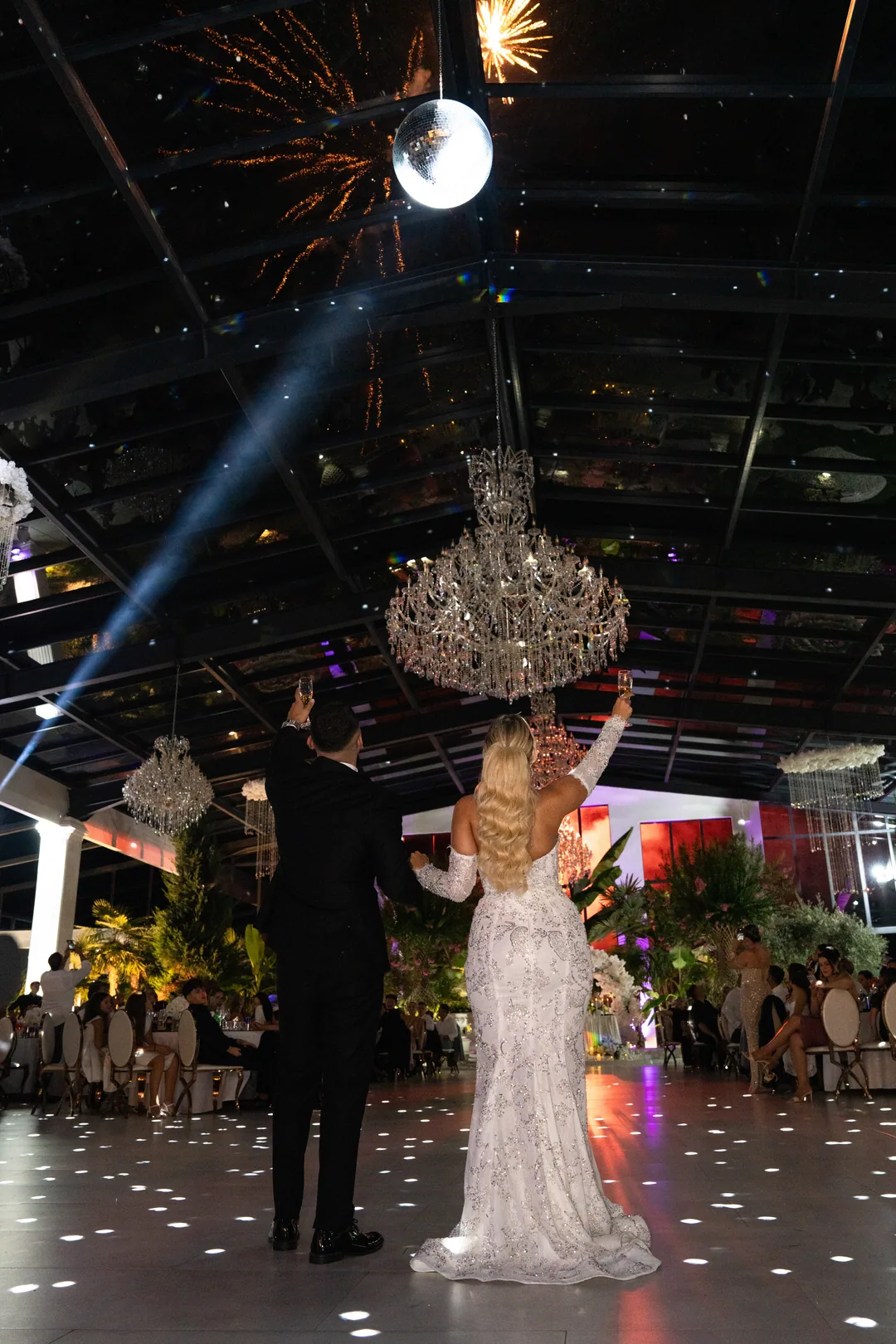 Couple on the dance floor under a crystal chandelier, fireworks and a mirror ball overhead