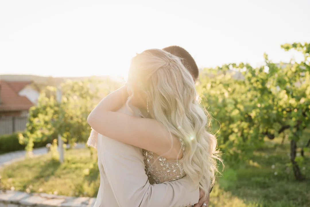 Couple embracing in the vineyard, the low sun flaring through her hair