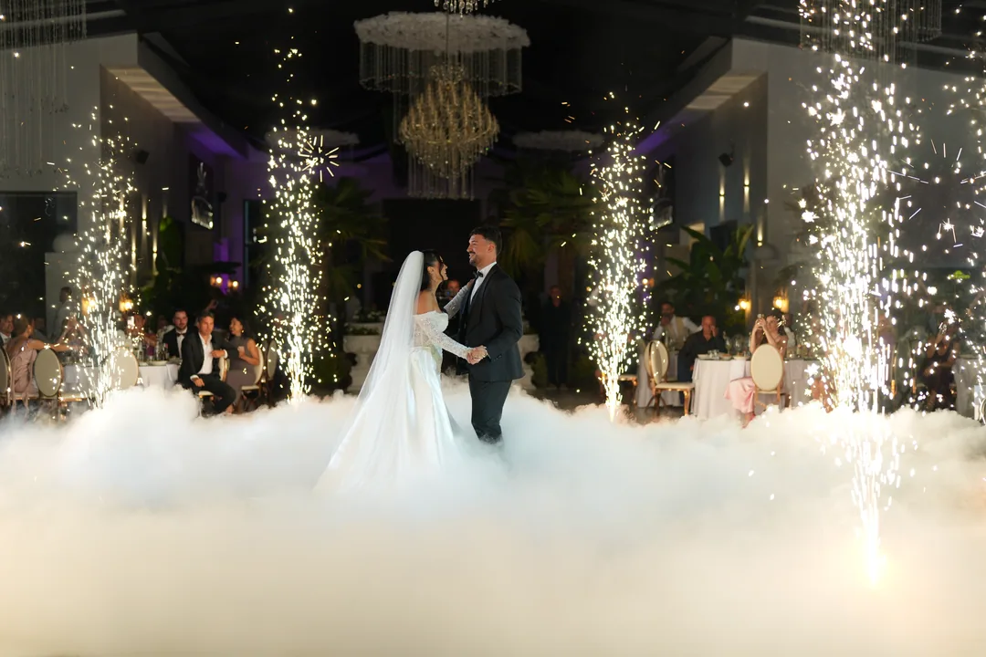 First dance on a cloud of low fog, sparkler fountains rising around the couple