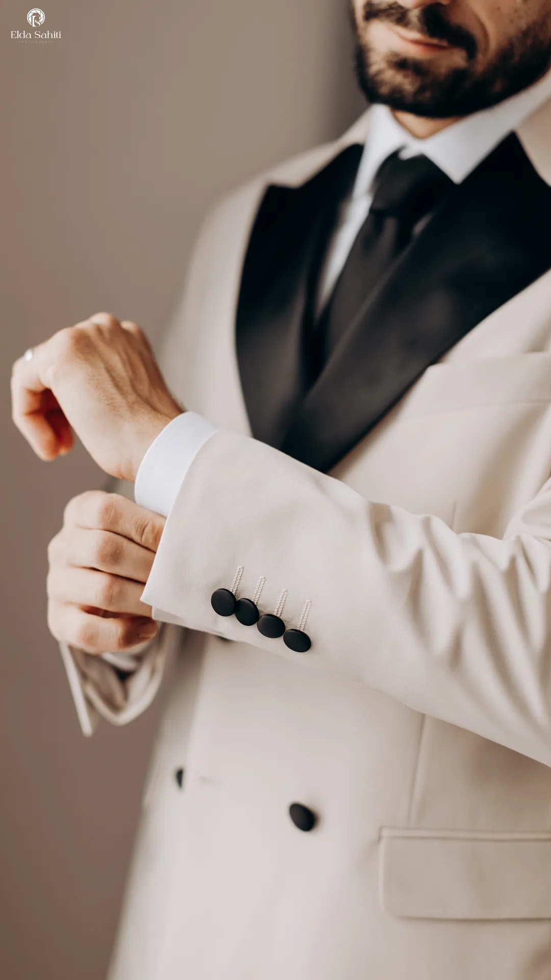 Groom fastening his cuff, a cream jacket with black lapels