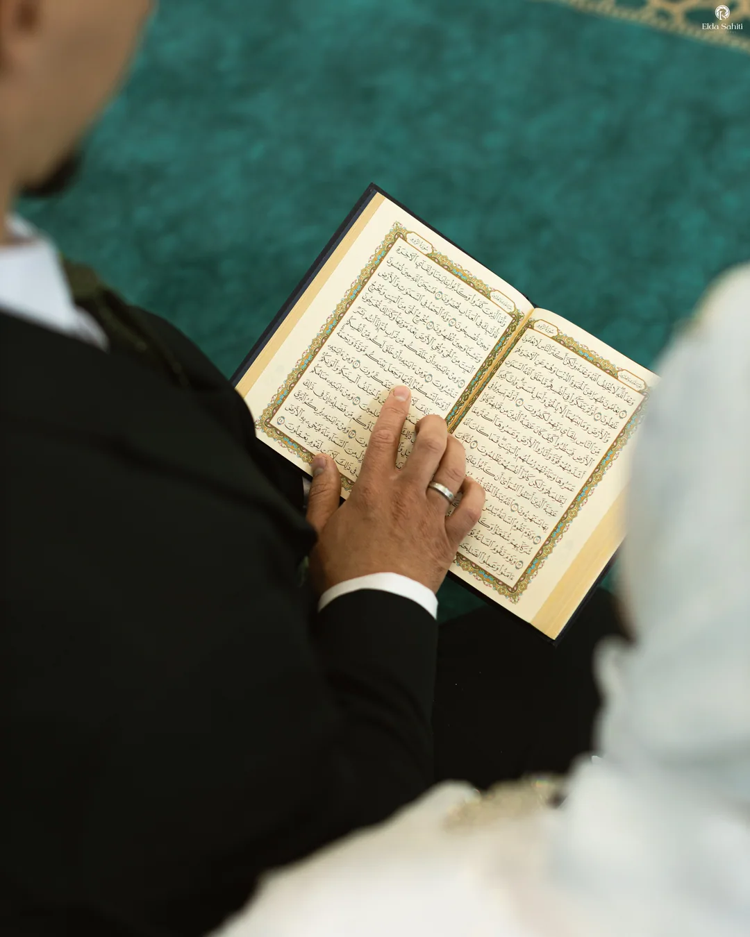 Groom's hand with his wedding ring holding an open Quran