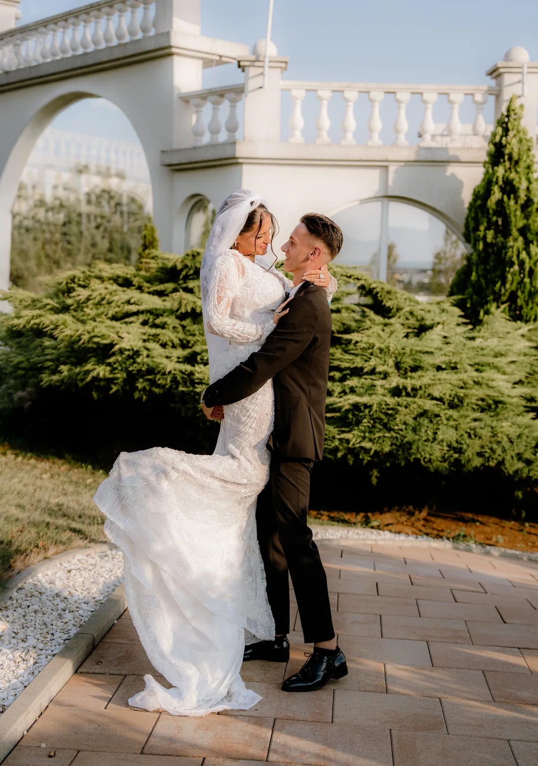 Groom lifting the bride on a garden path, her dress swinging out