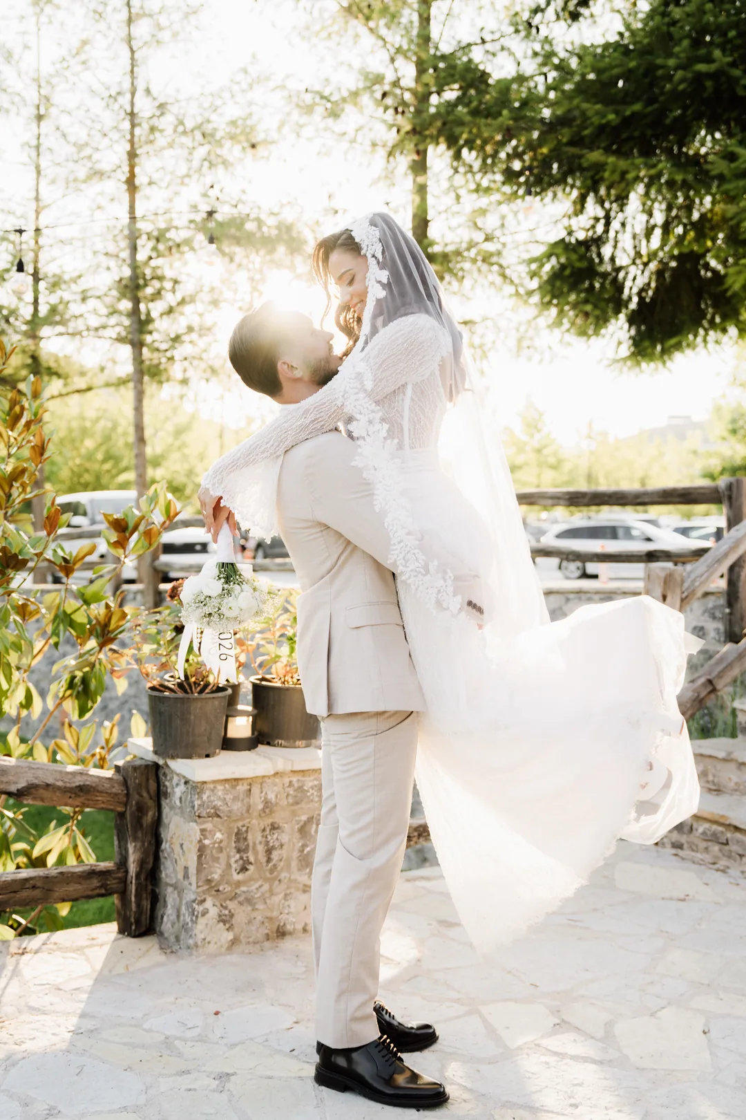 Groom lifting the bride, her veil flying as she smiles down at him