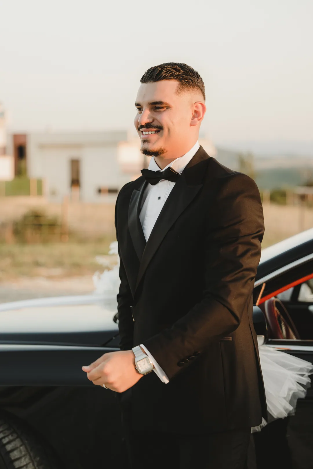 Groom smiling beside the open car door