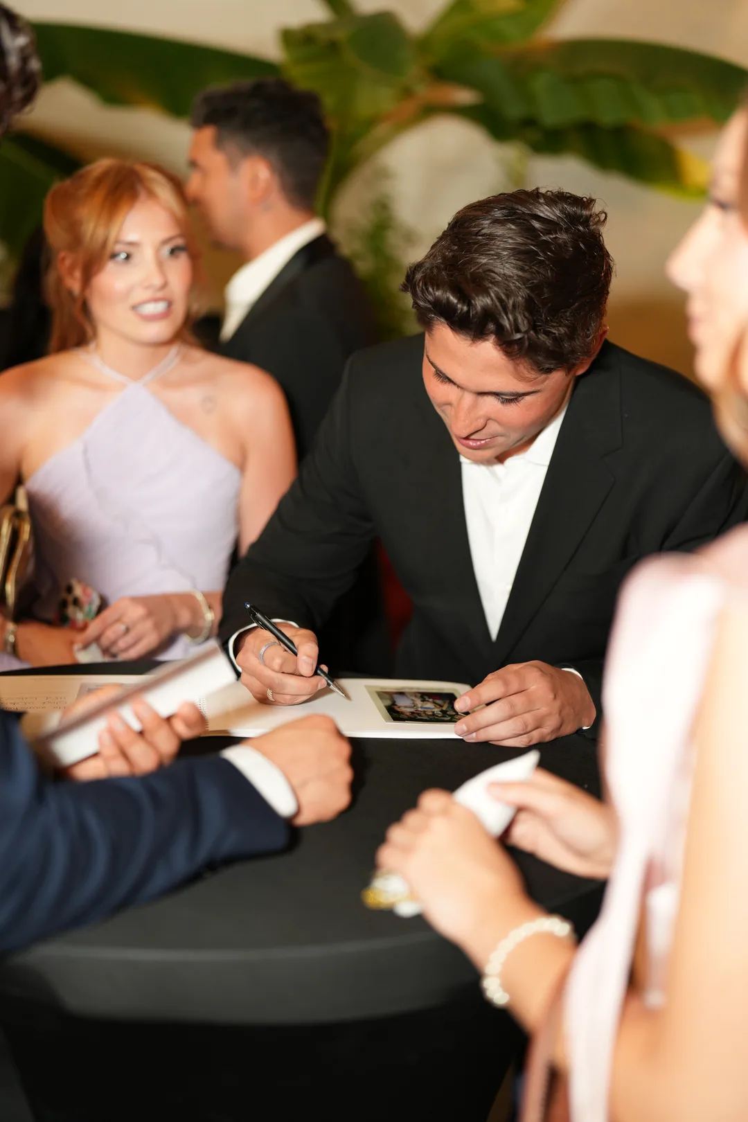 A guest signing a card at the cocktail table while friends look on