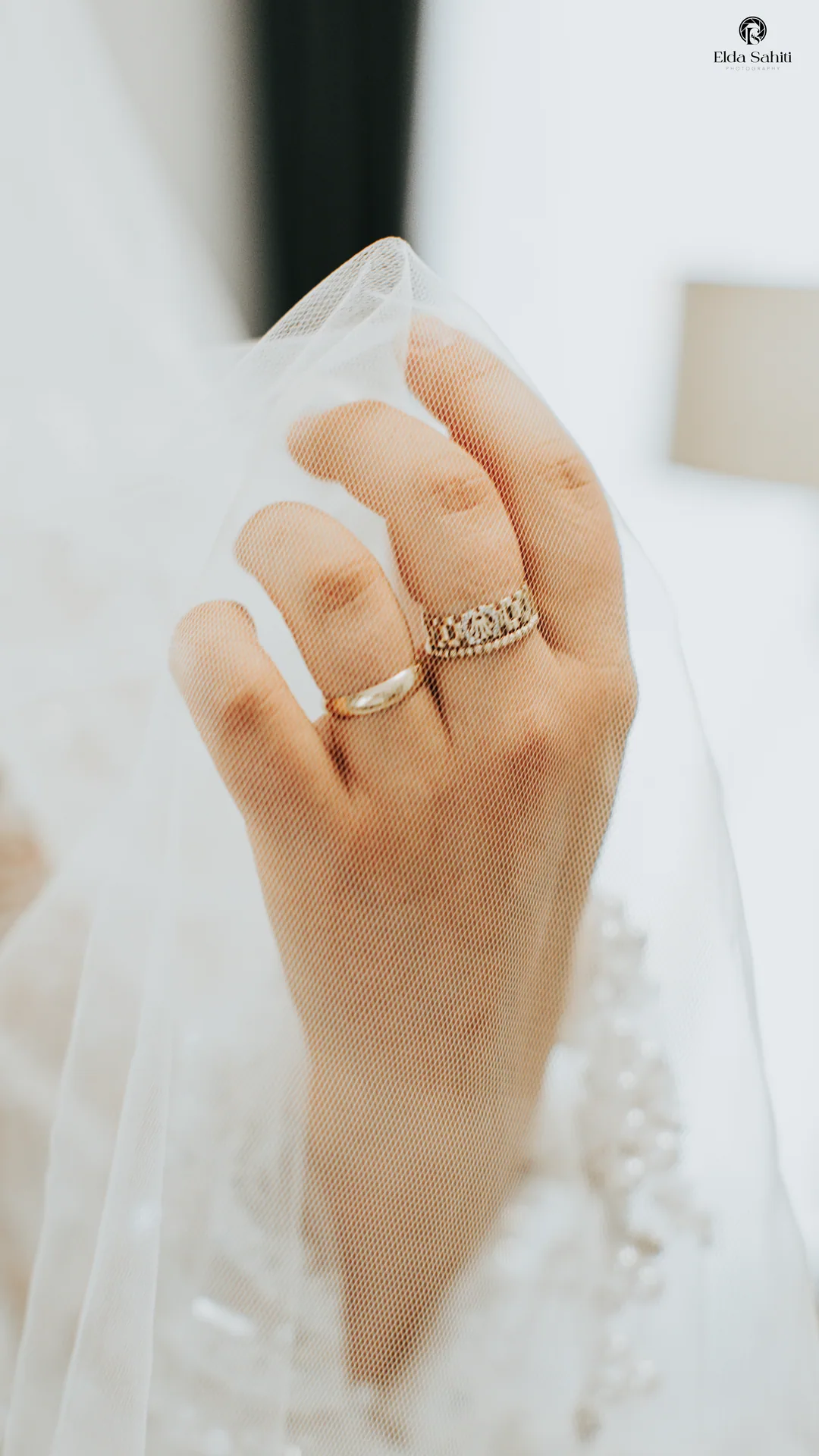 Bride's hand with two rings gathering the tulle of her veil
