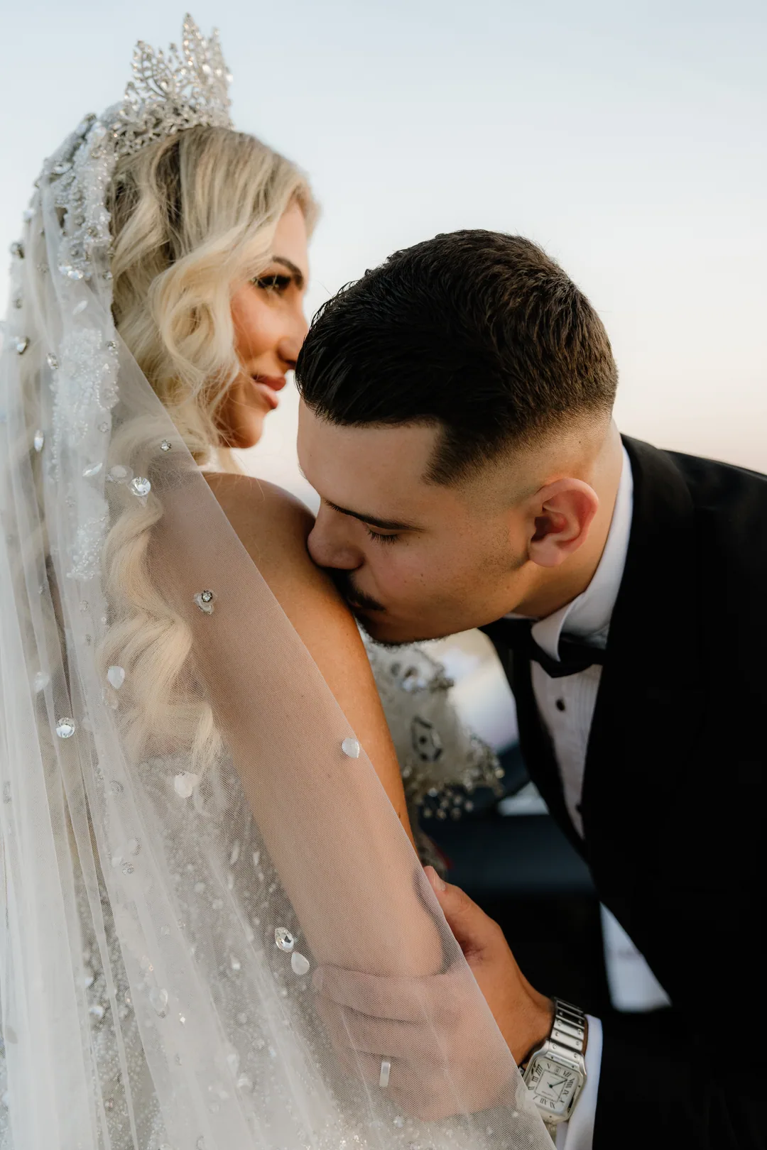 Close up: the groom's kiss on her shoulder, the bride smiling with her eyes lowered